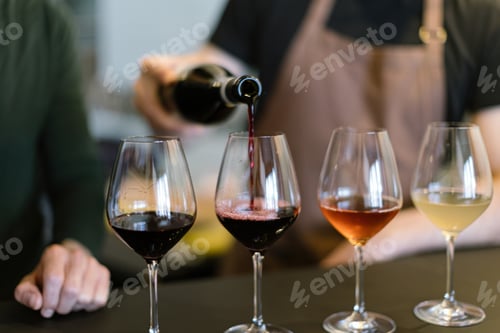 Preview: pouring different wines into the glasses arranged for the wine tasting on the counter