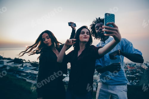 Preview: Group of young adult friends dancing in sunset and taking selfie