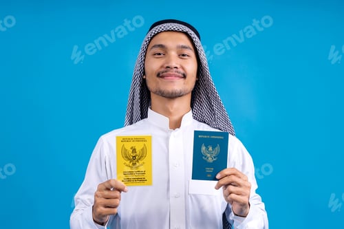 Preview: Smiling Young Arab Male Showing Passport And Health Declaration Card For Indonesian Pilgrims