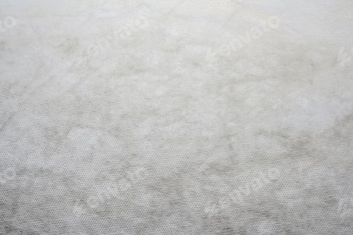 Preview: grey spunbond non-woven geotextile close-up macro. White surface. Close up. Small spots. Dirtied tex