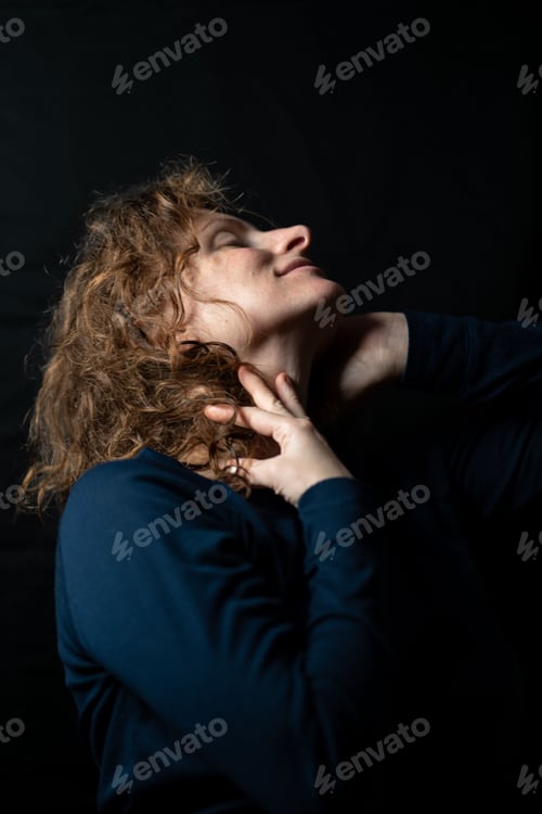 Preview: Sensual ginger model posing for a studio portrait, on a black background and studio light.