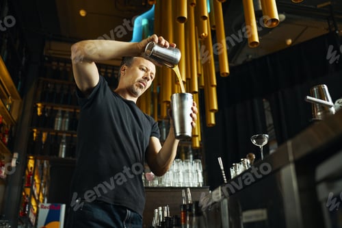 Preview: Middle Aged Caucasian Man Mixing Cocktail Behind Bar Counter in Modern Bar
