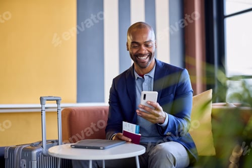 Preview: Smiling african businessman at airport using phone
