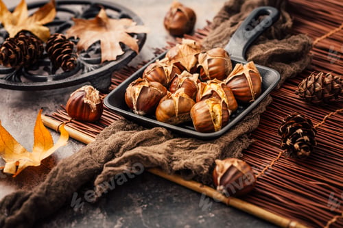Preview: Roasted chestnuts in iron pan on old kitchen table