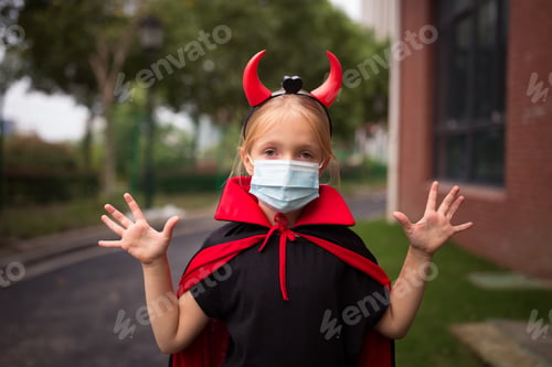 Preview: caucasian kid six-seven years old wearing protective face mask celebrating Halloween outdoor