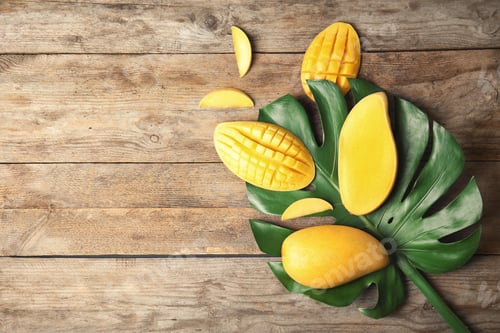 Preview: Flat lay composition with mango and tropical leaf on wooden background. Space for text