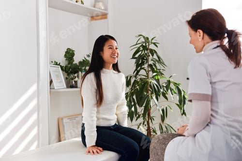 Preview: An Asian adult woman talking with a female doctor about vitamin consumption.