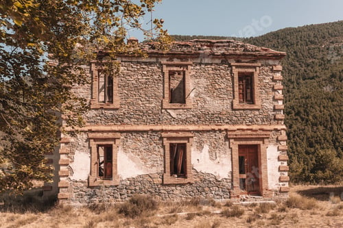 Preview: Exterior of an abandoned old brown stone house with trees with sunlight