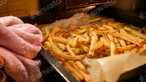 Preview: Closeup of taking baking pan with french fries potato out of oven.
