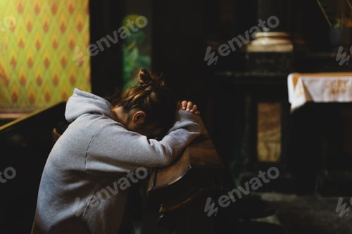 Preview: Woman praying on her knees in an ancient Catholic temple to God.