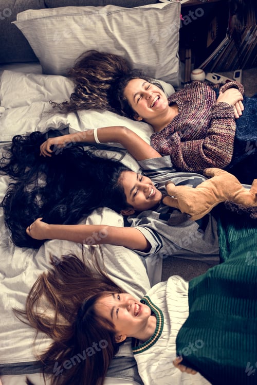 Preview: Teenage girls lying on the bed together with stuffed animal childhood and friendship concept