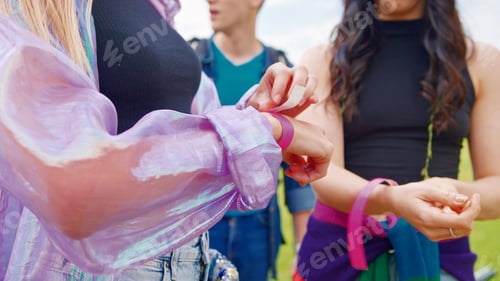Preview: Close Up Of Young Friends At Entrance To Music Festival Putting On Security Wristbands