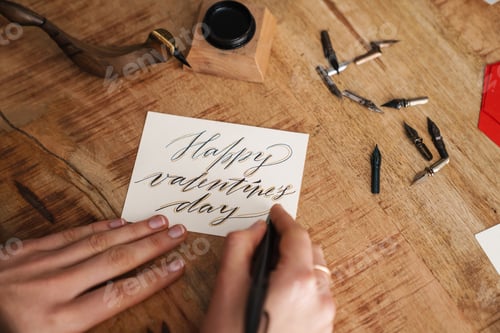 Preview: Calligrapher girl writing while working on valentines at table indoors