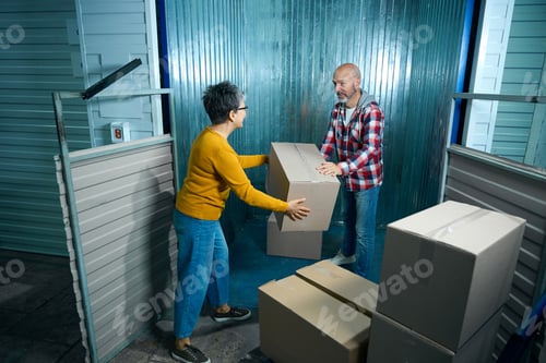 Preview: Adult man passing box to woman with glasses