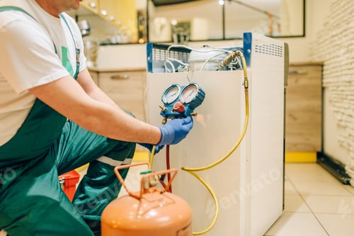 Preview: Worker in uniform fills compressor of refrigerator