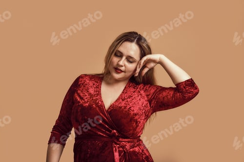 Preview: Enjoying my beauty. Plus size young woman in velour dress touching her face and keeping eyes closed