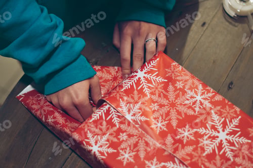 Preview: Hands of young woman is wrapping Christmas presents