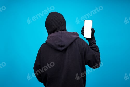 Preview: Rear View Of Mysterious Person Showing Smartphone Blank Screen Isolated On Blue Background