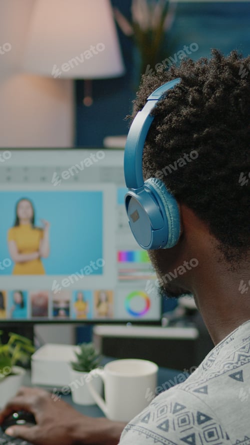Preview: Photographer retouching pictures on computer and wearing headphones