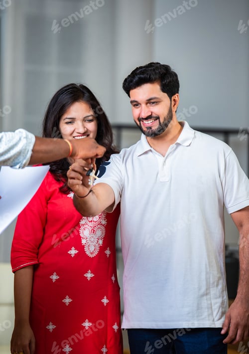 Preview: Happy Indian young couple buying their new home and receiving keys from real estate agent.