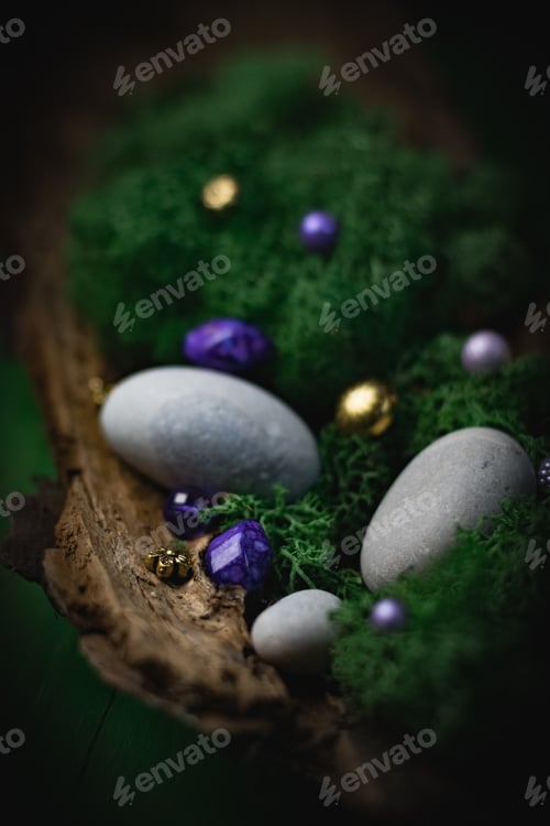 Preview: Lilac, golden natural stone lies in the bark of a tree with moss and gray stones on a green