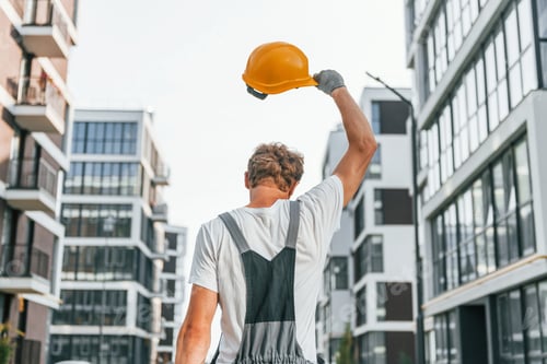 Preview: Results of work. Young man in uniform at construction at daytime