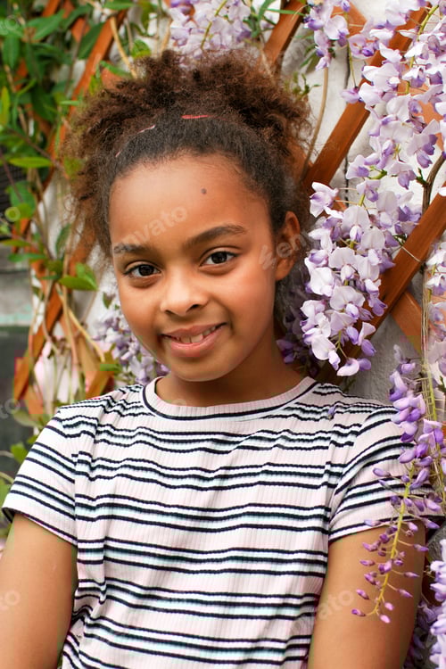 Preview: Portrait of Generation Z girl in front of purple wisteria flowers - petals pink mixed race diversity