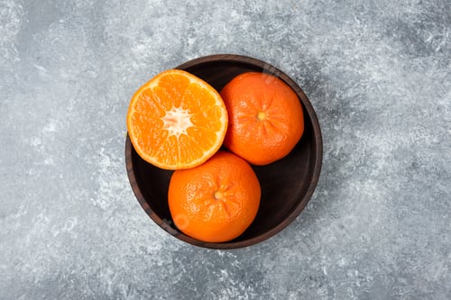Preview: A wooden bowl full of juicy orange fruits on stone background