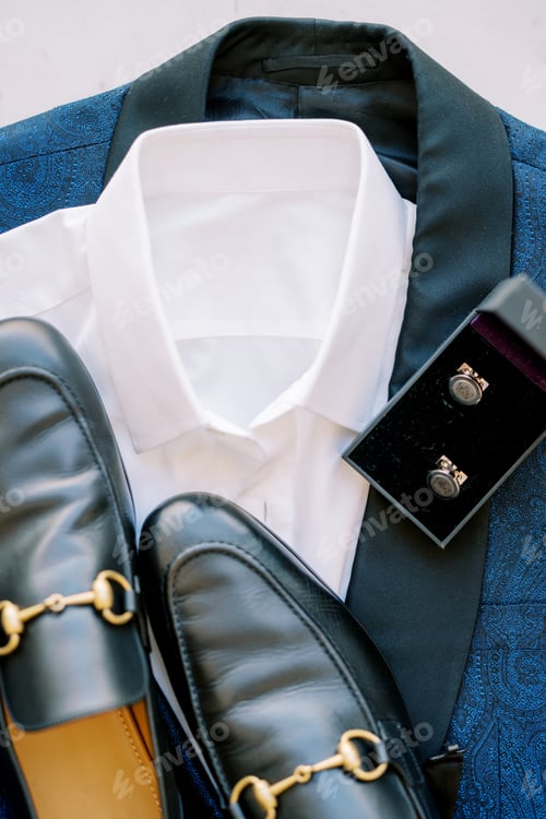 Preview: Black men shoes stand on a blue suit next to cufflinks in a box