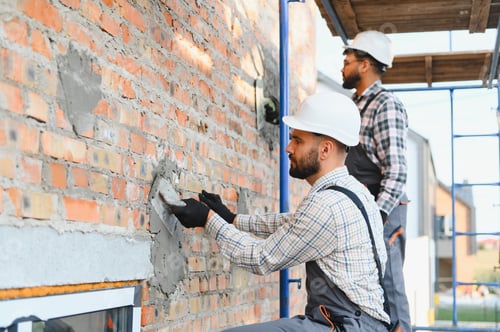 Preview: Construction workers plastering brick wall during building renovation process