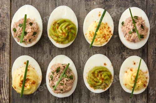 Preview: Deviled eggs with various toppings sitting on rustic wooden table