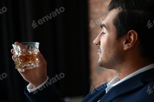 Preview: Young man with glass of whiskey indoors
