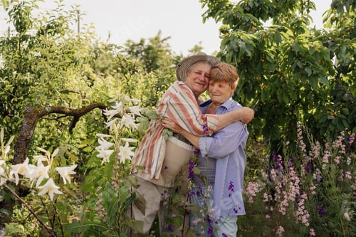 Preview: Happy senior couple hugging and cuddling in the garden with trees and flowers. Healthy lifestyle