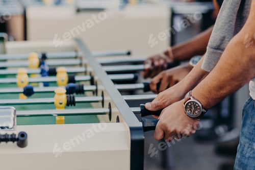 Preview: Men play table football, enjoy team game, want to win opponents, spend free time in pub. Kicker game