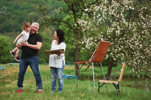 Preview: Grandmother and grandfather have fun outdoors with granddaughter. Painting conception