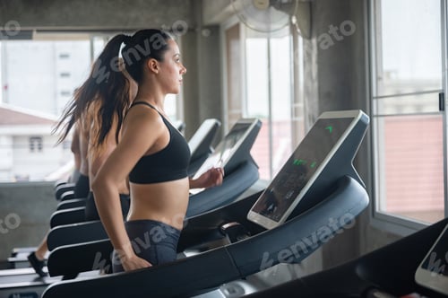 Preview: Group of young shirtless man and woman in sportswear working on elliptical machine for cardio