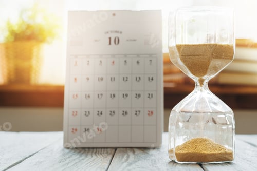 Preview: Hourglass with calendar on wooden desk close up