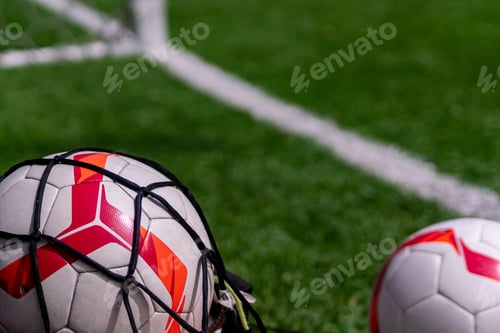 Preview: Football balls in a mesh on green pitch background. Sports game