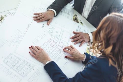 Preview: Close-up of businesswoman and businessman working on plan on desk in office