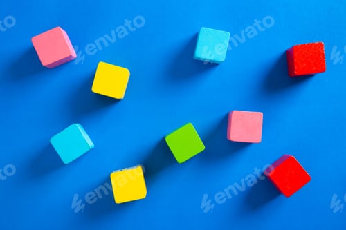 Preview: Colorful wooden cubes arranged on blue background creating playful composition