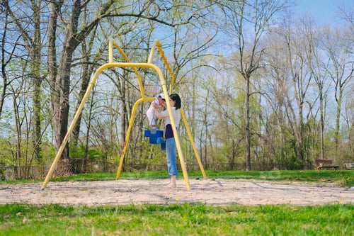 Preview: Mother and diverse toddler girl bonding together as a family on a nice summer day at playground park