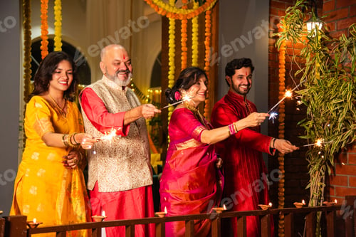 Preview: Indian family with grandparents and kids celebrating Diwali by lighting sparklers and firecrackers