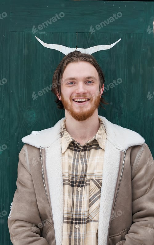 Preview: Young guy walking near red barn,green door.Deer,elk,bull antlers drawing.Snowy cold winter in