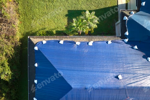 Preview: Top view of leaking house roof covered with protective tarp sheets against rain water