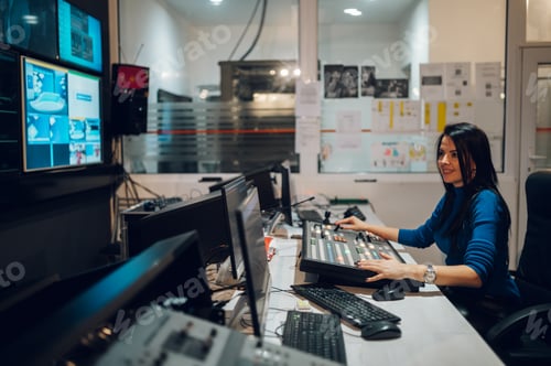 Preview: Middle aged woman working on a tv station as a producer in a broadcast control room