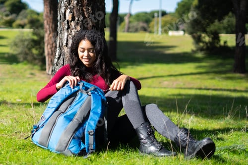 Preview: Young latin tourist exploring nature opening backpack in nature