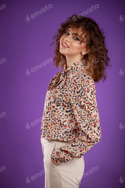 Preview: A vertical portrait of a young curly-haired girl smiling and standing on purple background