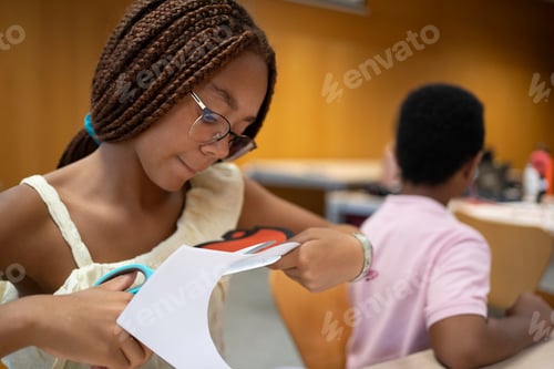 Preview: Young afro girl learning crafting skills cutting paper