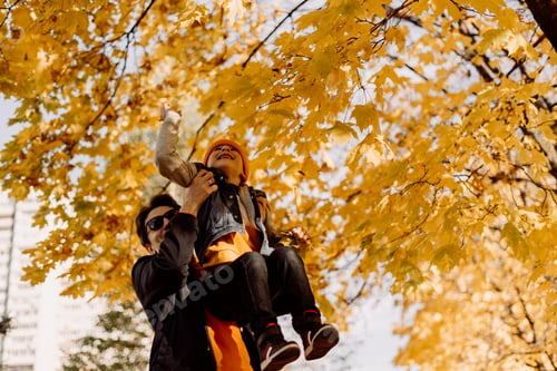 Preview: Father and son having fun in autumn park with fallen leaves, throwing up leaf. Child kid boy and his