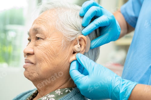 Preview: Audiologist or ENT doctor use otoscope checking ear of asian senior woman patient treating.
